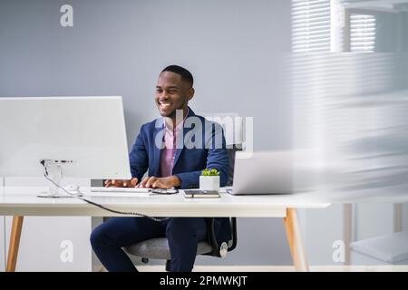 African Businessman Banner Using Computer In Office Stock Photo