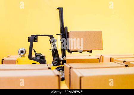 Forklift truck raises cardboard boxes on a yellow background. Cargo ...