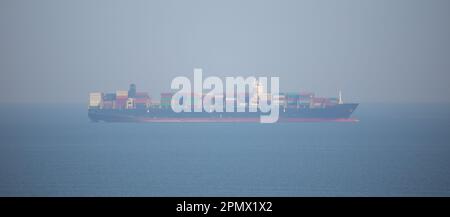 immense cargo ship, fully loaded with shipping containers, cruising through the open waters of the ocean Stock Photo