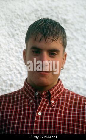 Portrait of a Young Man Wearing a Red and White Checkered Shirt With Earring in one Ear Stock Photo