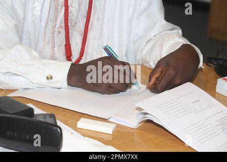 Close Up of African Man Wearing Traditional Dress Filling in Paperwork at Business Conference England Stock Photo