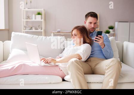 Family Couple Using Laptop And Phone On Couch Stock Photo