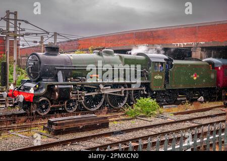 Jubilee class steam locomotive named Bahamas passing south through Warrington Bank Quay station on the West Coast Main Line. In the rain on a gray day Stock Photo