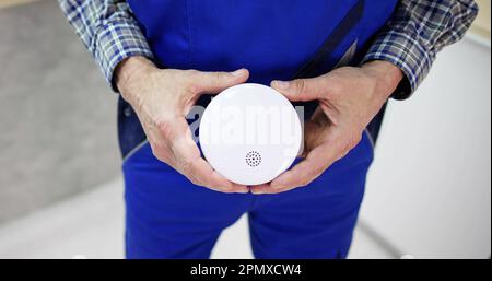 Electrician Holding Smoke Detector. Fire Alarm Test And Installation Stock Photo