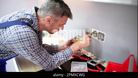 Close-up Of Person Hand Metering Socket Voltage With Digital Multimeter Stock Photo