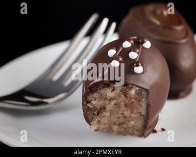 Macro shot of two noble and artfully decorated marzipan chocolates. On a porcelain plate with cake fork. Stock Photo