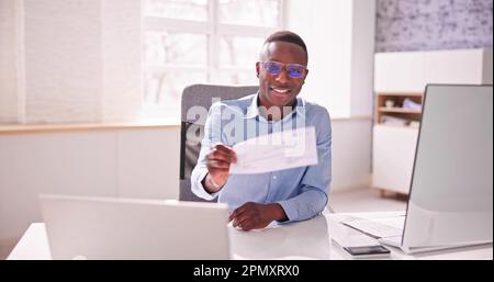 Holding Paycheck Or Payroll Check Or Insurance Cheque In Hand Stock Photo