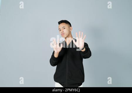 a young man wearing a black shirt showing a rejecting gesture Stock Photo