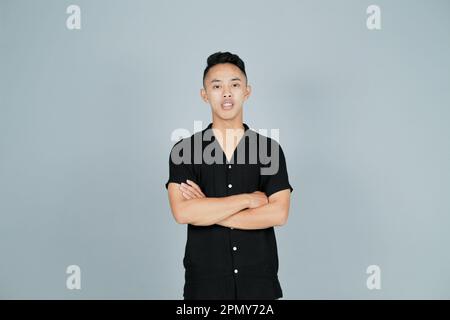 a confident smiling young man wearing a black shirt and folded arms Stock Photo