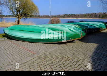 a lot of plastic boats in green color on the shore. Stock Photo