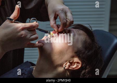 Dentist working with a patient in a dental office. The doctor makes an injection of anesthetic into the gum closeup Stock Photo