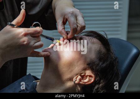 Dentist working with a patient in a dental office. The doctor makes an injection of anesthetic into the gum closeup Stock Photo