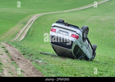 Big SUV car after rollover on the roof in nature. Car crash in agricultural field. Accident on dusty rural road. Isolated, deformed crashed overturned Stock Photo