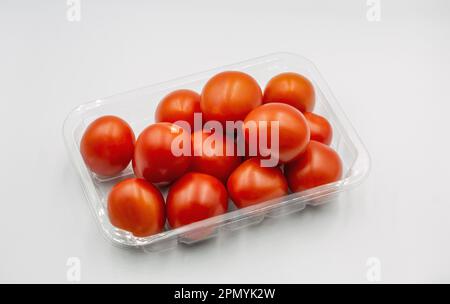 Small cherry tasty red fresh tomatoes in plastic package closeup on white Stock Photo
