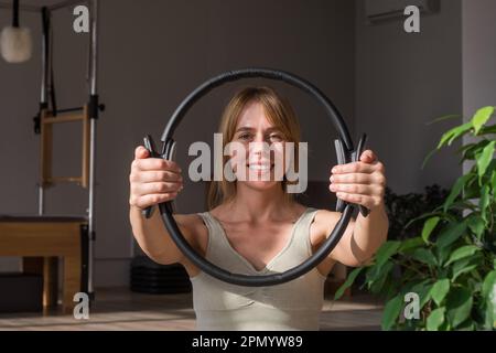 Young sporty attractive women doing pilates toning exercises for abs with flex ring toner,, crunches to strengthen abdomen using pilates magic circle Stock Photo