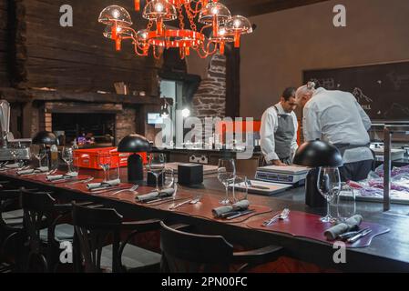 Chefs working in kitchen by dining table at luxury restaurant Stock Photo