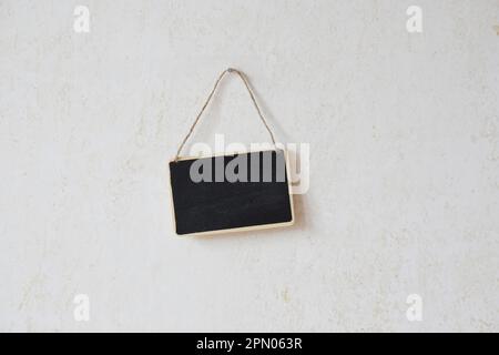 small blank chalkboard sign with piece of string hanging on nail Stock Photo