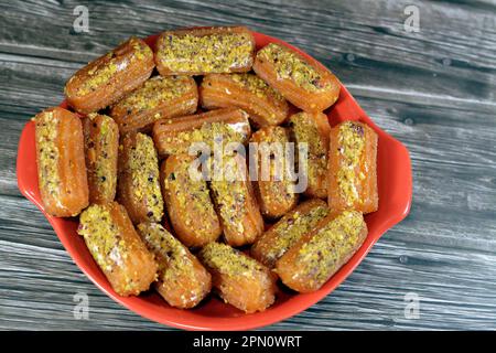 Tulumba, Bamiyeh or Balah El Sham stuffued with whipped cream and covered with pistachios and nuts, deep fried batter dessert soaked in syrup, similar Stock Photo