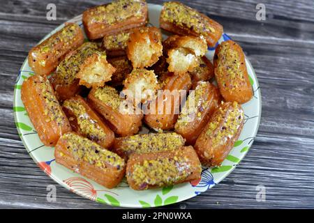 Tulumba, Bamiyeh or Balah El Sham stuffued with whipped cream and covered with pistachios and nuts, deep fried batter dessert soaked in syrup, similar Stock Photo