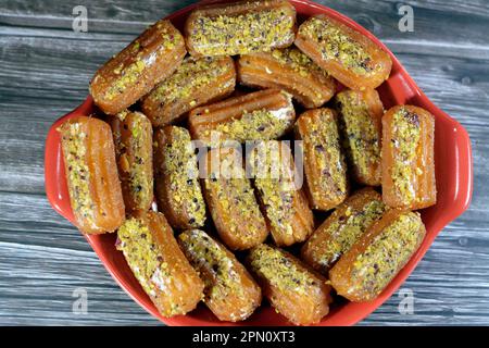 Tulumba, Bamiyeh or Balah El Sham stuffued with whipped cream and covered with pistachios and nuts, deep fried batter dessert soaked in syrup, similar Stock Photo