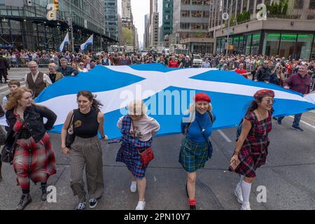 NEW YORK, NEW YORK - APRIL 15: Participants carrying a large Scottish flag march at the 25th Annual Tartan Day Parade in Manhattan on April 15, 2023 in New York City. Stock Photo