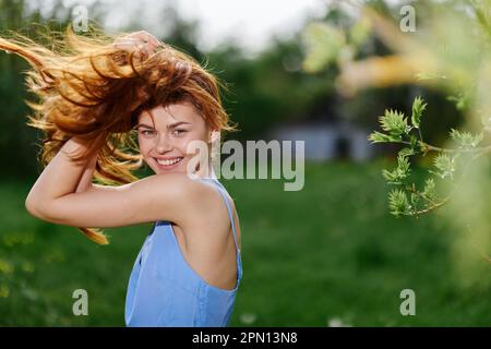 Woman beautiful smile with teeth in the spring on a sunny day happy in nature against the backdrop of green grass, the concept of female body health Stock Photo