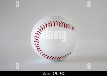 Close-up of a white baseball with red stitching on a grey background Stock Photo