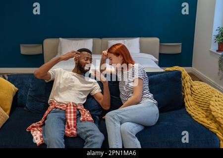 Young happy interracial family couple husband and wife bonding at home, talking and laughing Stock Photo