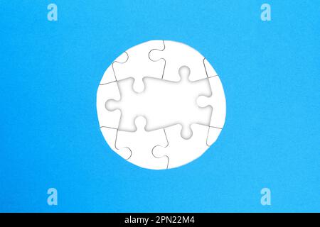 Frame of white puzzles on blue background. Place for your text. Mockup Stock Photo