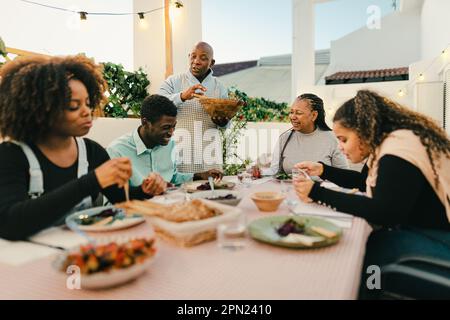 Happy African family dining together on house patio - Family Gatherings concept Stock Photo
