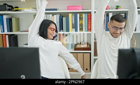 Man and woman students using computer stretching arms at university classroom Stock Photo