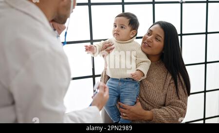 Couple and son examining baby with stethoscope at clinic Stock Photo