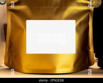 Close Up empty blank white label on modern gold foil bag coffee beans packaging. Mockup template sticker label. Front of paper zipper pouch packaging Stock Photo