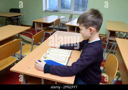 Classroom of the medrese. Muslim boy sitting at a school desk, Quran placed in front of him. October 21, 2018. Islamic culture centre, Kiev, Ukraine Stock Photo