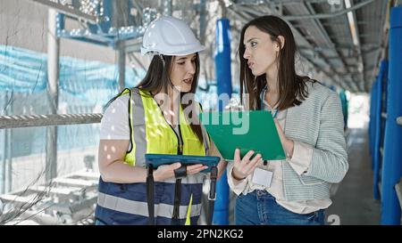Two women architect and worker using touchpad and clipboard working at street Stock Photo
