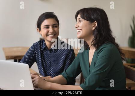 Happy Indian and Armenian women talking, working together in office Stock Photo