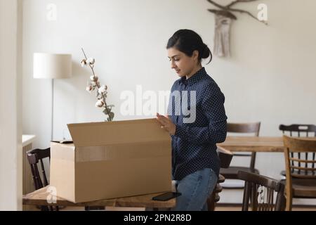 Indian woman get parcel, open box to review received goods Stock Photo