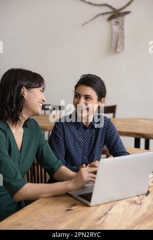 Two women colleagues talking laughing in office at workplace Stock Photo
