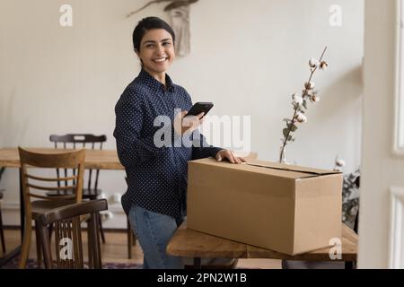 Satisfied Indian woman sending parcel using courier on-line services Stock Photo