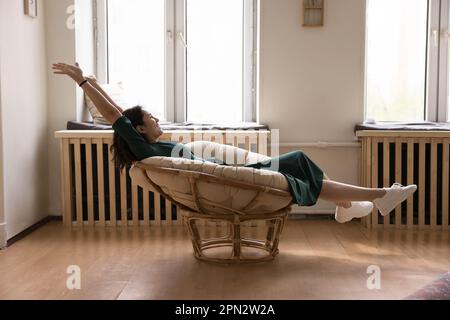 Happy young woman relaxing seated in modern chair Stock Photo
