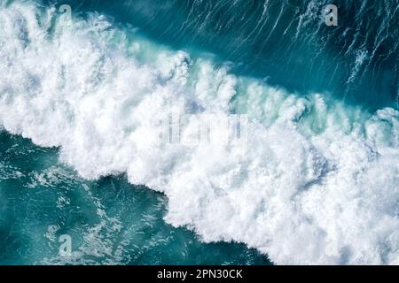 Experience the sheer might of the ocean as a colossal wave breaks and creates a tumultuous display of frothy white foam and turbulent waters. Stock Photo