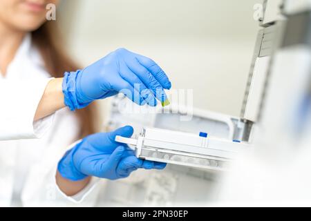 conducting chemical experiments in modern devices in a research laboratory. inserting the container with the solution into the measuring device Stock Photo