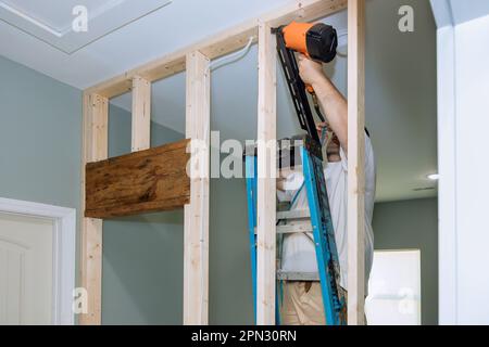 An air hammer is being used by a builder to nail wooden beams during ...