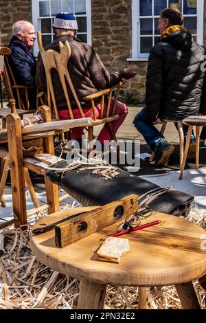 Hand-made chairs on a carpenter's stall in Bridport Saturday Street Market. Concept artisan, craftsman, carpenter's tools, half biscuit and spectacles. Stock Photo