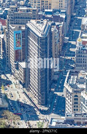 Flatiron Building, a NYC icon, viewed through haze from another icon, the Empire State Building. Renovation scaffolds obscure the façade. Stock Photo