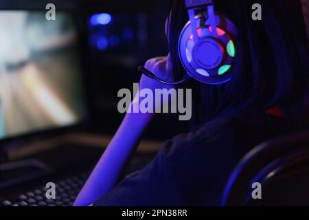 Female cyber hacker gamer in headphone serious face to playing games or hacking programming system. Stock Photo