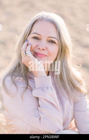 a beautiful gray-haired elderly woman on the street looks into the camera and smiles. The concept of a happy and beautiful old age Stock Photo