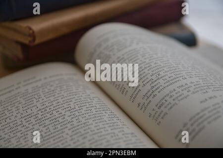 Image of an out of focus and inverted page of an old book, next to it other old books Stock Photo