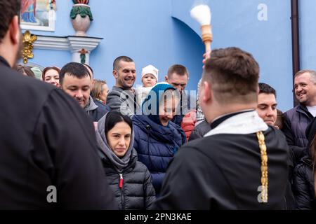 A priest blesses Ukrainian believers with Holy Water as they attend the Easter Sunday traditional celebration in St. Michael's Golden-Domed Monastery in central Kyiv, the capital of Ukraine on April 16, 2023. According to the tradition the faithful bring their Easter food in a basket to be purified, it always is Pasha (Easter bread), painted egg (pysanka) among other. Most of Ukrainians are Orthodox Christians or Greek Catholic Christians, both observe the eastern rite of Easter. Kyiv remains relatively peaceful as the Russian invasion continuous and Ukraine prepares for a spring counter-offen Stock Photo