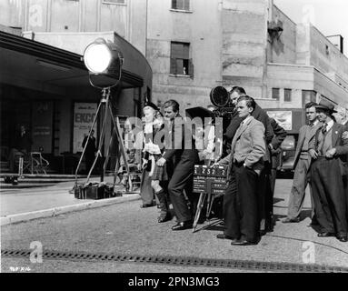 BELINDA LEE and BENNY HILL on set location candid with Film / Camera Crew during filming of WHO DONE IT ? 1956 director BASIL DEARDEN story / screenplay T.E.B. Clarke costume design Anthony Mendleson co-producers Basil Dearden and Michael Relph executive producer Michael Balcon Ealing Studios / Michael Balcon Productions / The Rank Organisation Stock Photo